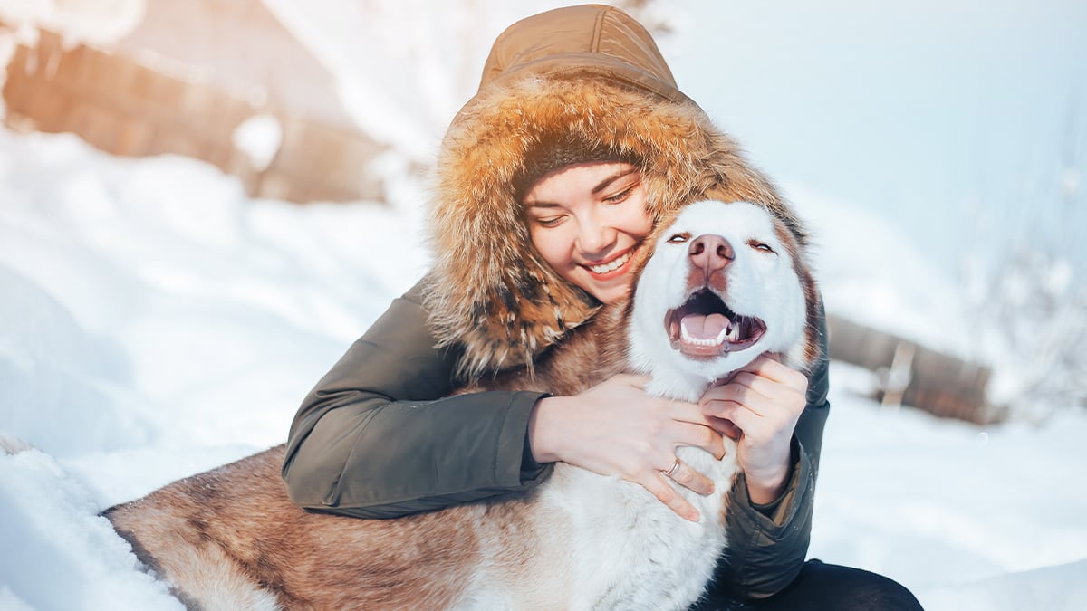 Hund im Winter Eine Frau hockt mit ihrem Hund im Schnee.